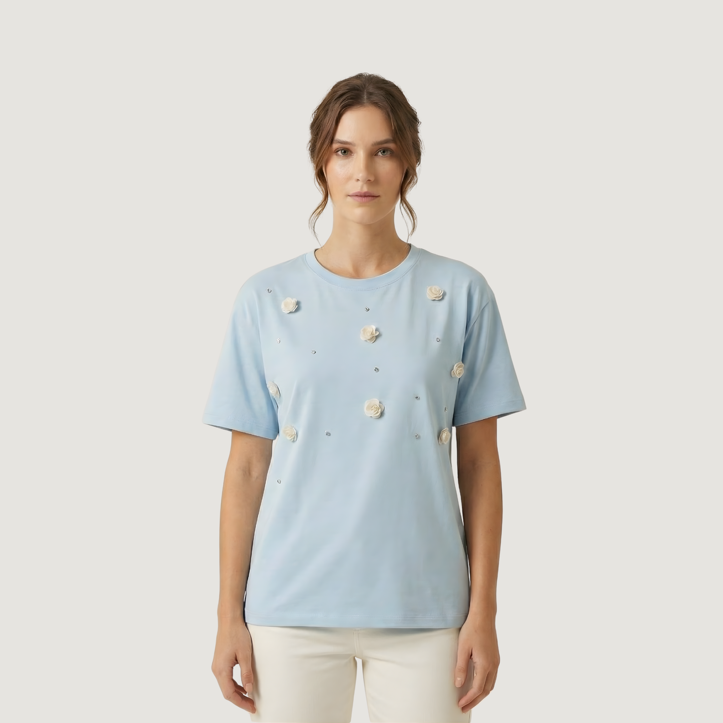 Woman wearing a light blue t-shirt with floral patterns on a plain background